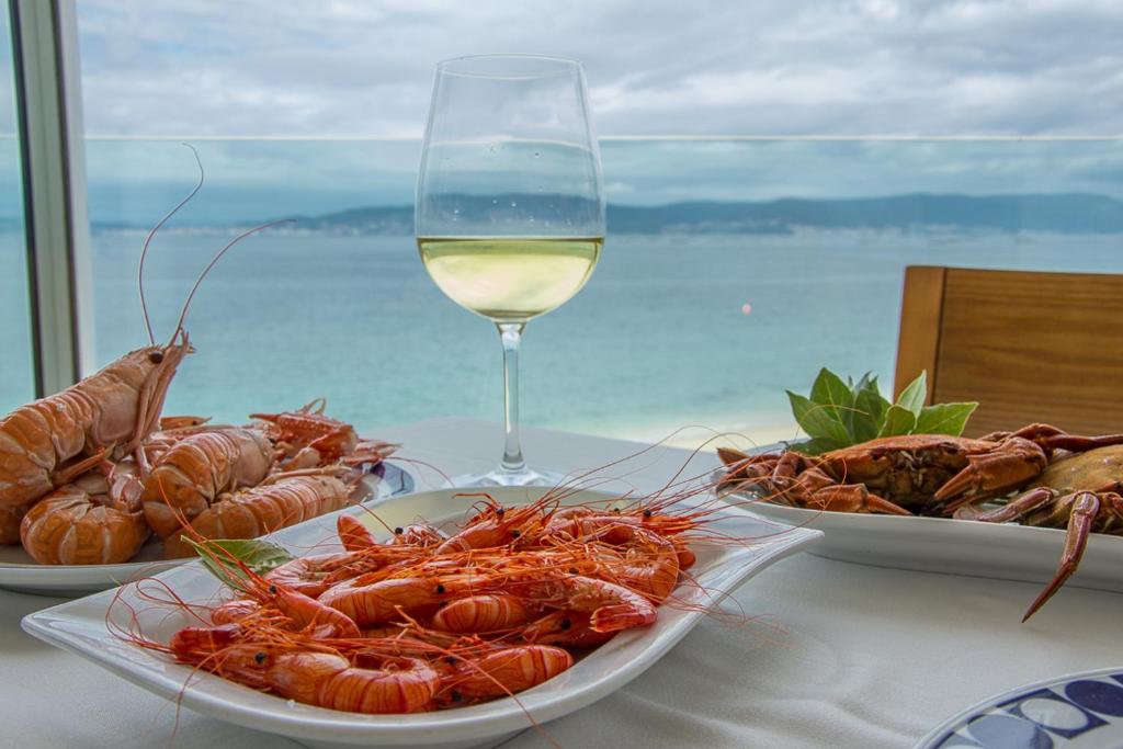 布埃烏的住宿－餐廳洛雷羅酒店，一张桌子,上面放着三盘龙虾和一杯葡萄酒