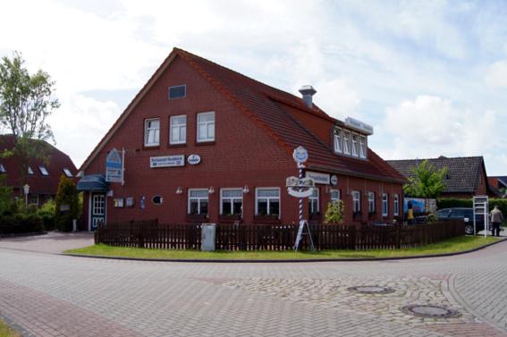 - un grand bâtiment rouge avec un panneau devant dans l'établissement Gästehaus Restaurant Norddeich, à Norddeich