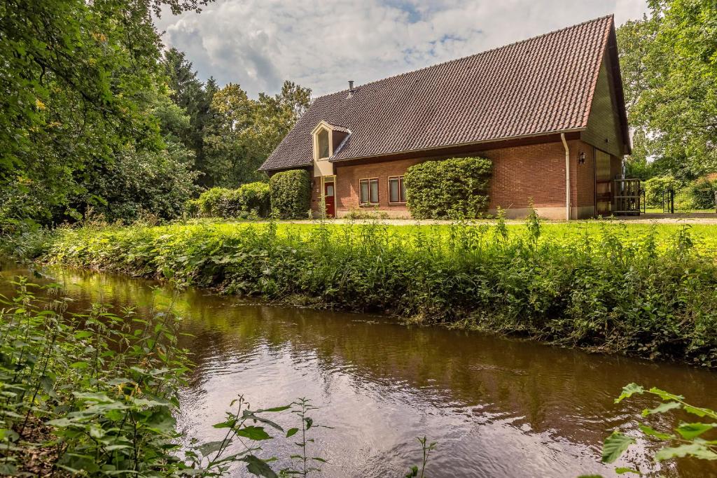 ein Haus mit einem Fluss davor in der Unterkunft Bed & Breakfast aan de Beek in Arcen