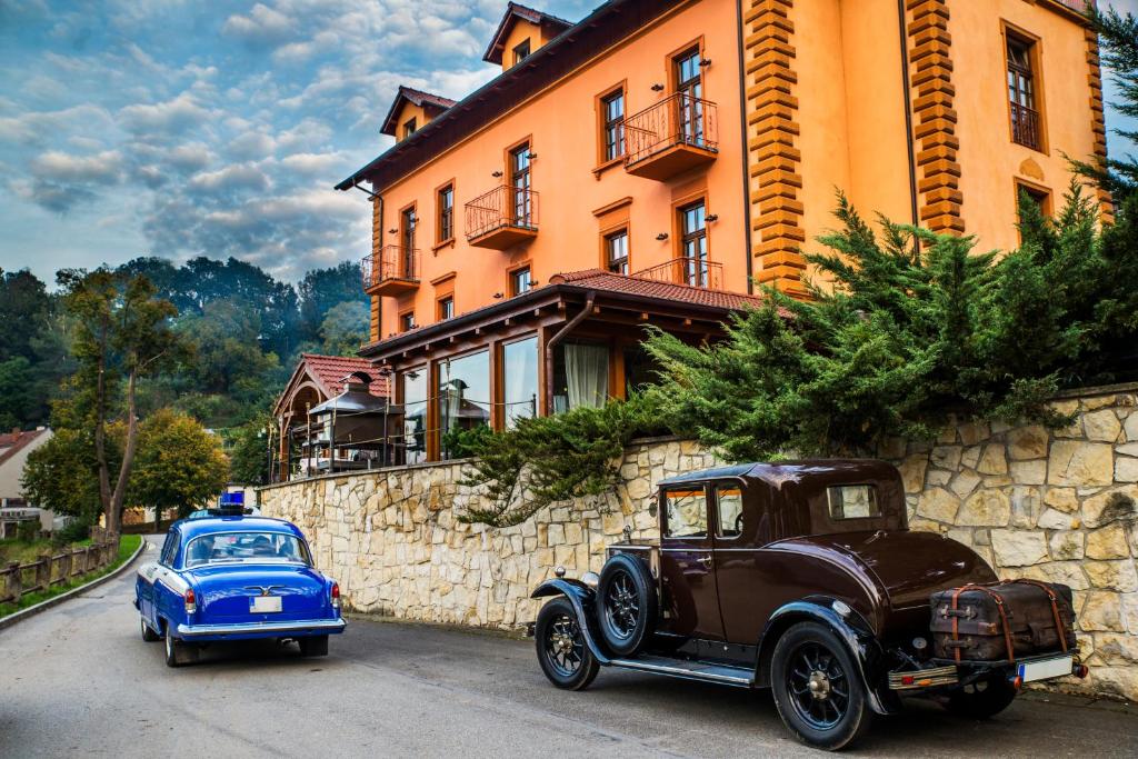 une vieille voiture et une voiture bleue garées devant un bâtiment dans l'établissement ROMANTIK HOTEL ELEONORA, à Tábor