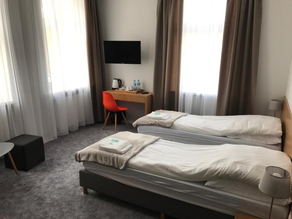 Habitación de hotel con 2 camas y escritorio en 7 Rooms MTP, en Poznan
