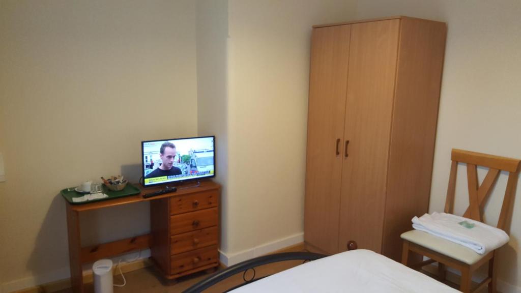 a bedroom with a television on a wooden dresser at Cedars House Hotel in Croydon