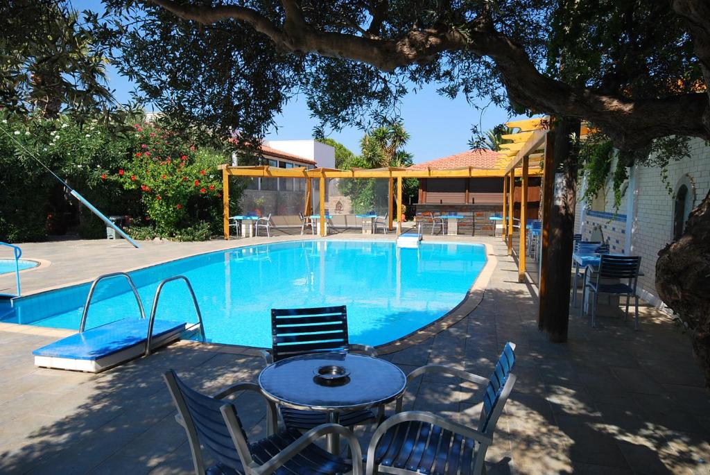 a table and chairs next to a swimming pool at Hotel Marina Village in Palekastron