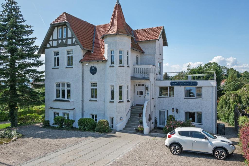 een auto geparkeerd voor een groot huis bij Hotel Sønderborg Garni in Sønderborg