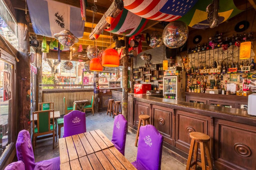 埃斯特角城的住宿－The Trip Hostel，一间酒吧,配有紫色椅子和木桌