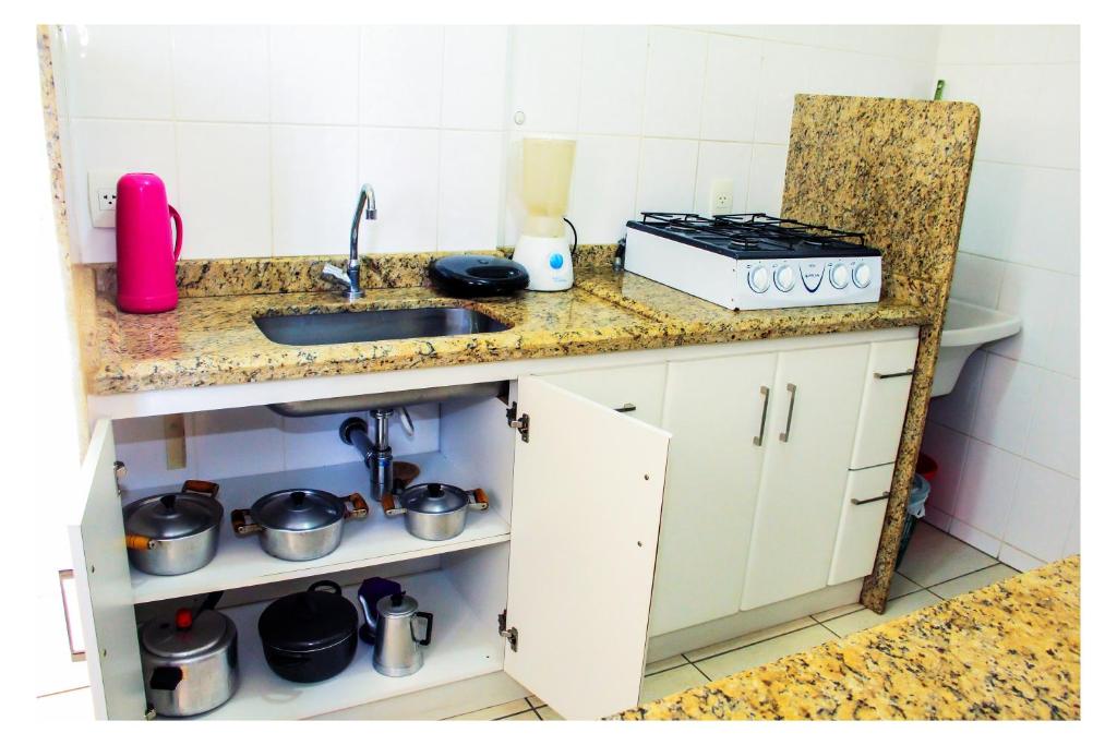 cocina con fregadero y encimera con ollas y sartenes en Flats em Goiania, en Goiânia