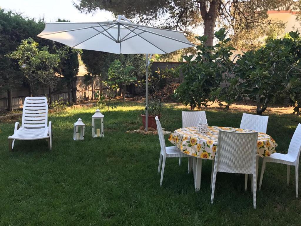 a table and chairs with an umbrella in the grass at Villa Lu in Porto Cesareo