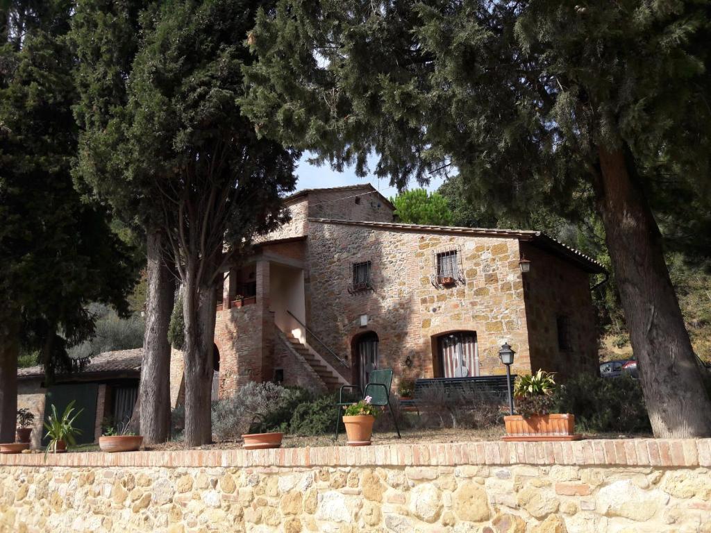 a stone house with trees in front of it at Agriturismo Podere San Pietro in Montepulciano