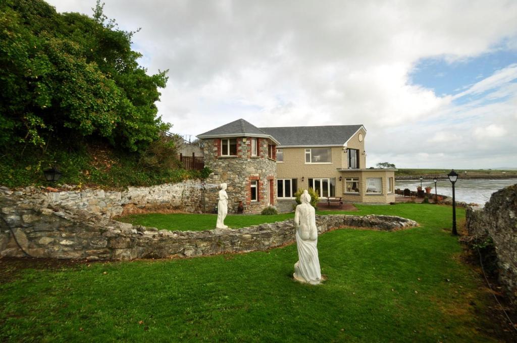 una casa con due statue di fronte a un muro di pietra di Barrow Lodge a Tralee