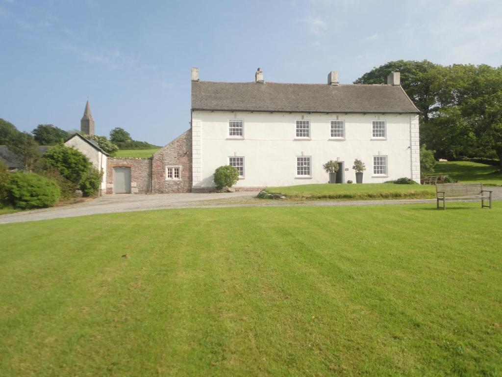 a large white house with a large grass field at Rame Barton Guest House and Pottery in Cawsand