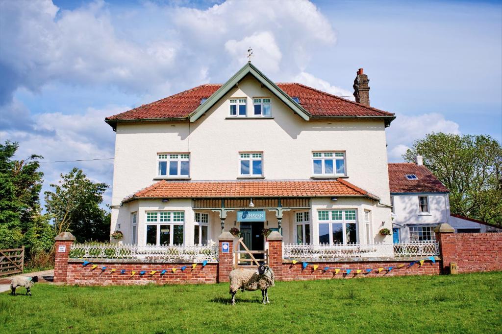 two sheep standing in the grass in front of a house at Fairhaven Country Guest House in Goathland