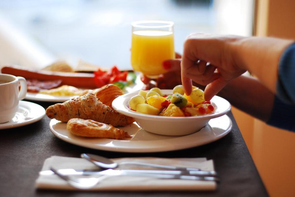 a person eating a bowl of breakfast food on a table at Hotel Porto Calpe in Calpe