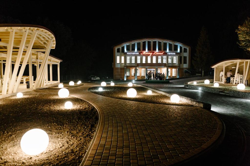 un edificio con luces delante de él por la noche en Hotel Merry Land, en Horodenka