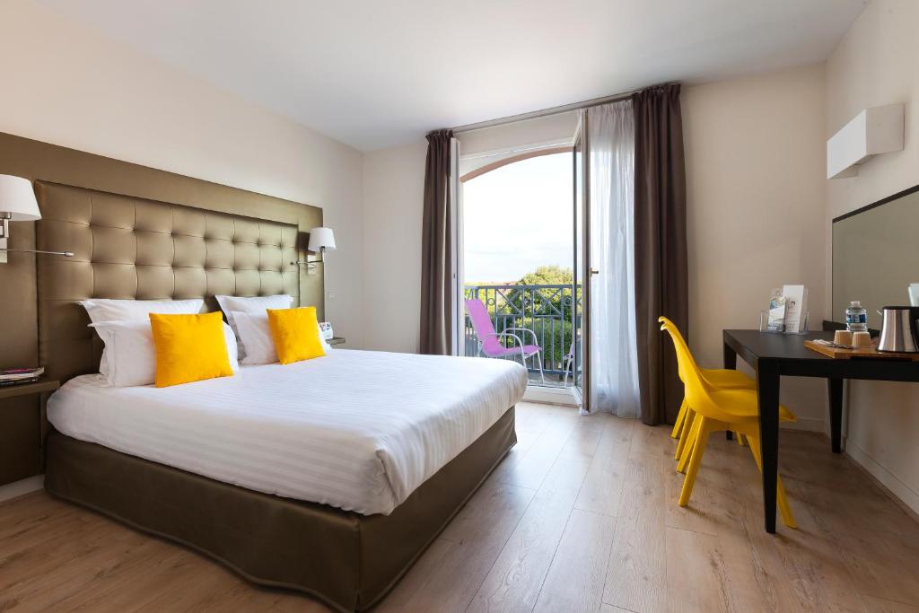 a hotel room with a bed and a desk and a window at Best Western Hotel du Chateau Maisons Laffitte in Maisons-Laffitte