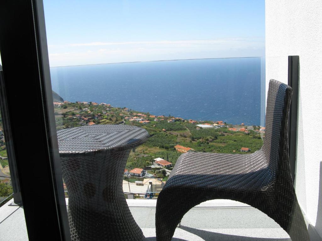 una sedia seduta su un balcone affacciato sull'oceano di Villa Girasol ad Arco da Calheta