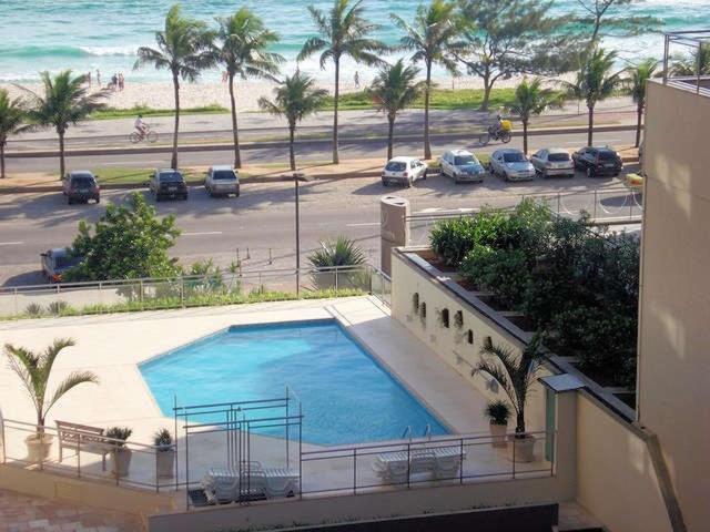 a large swimming pool on the side of a building next to the beach at Apartamento na Praia da Barra in Rio de Janeiro