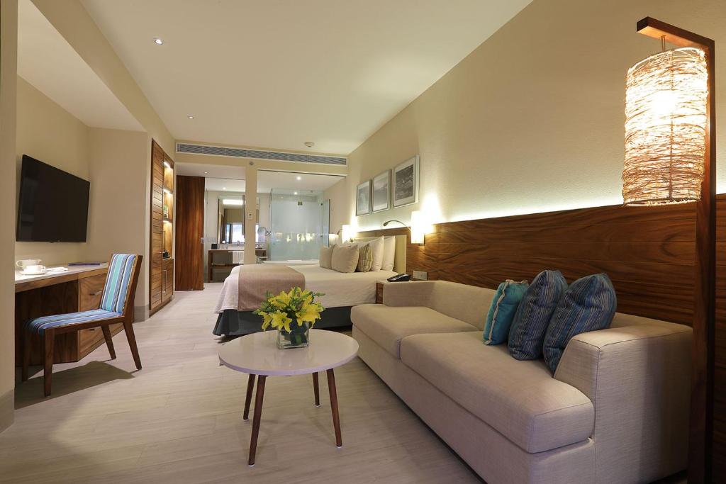 a living room with a couch and a bed at Emporio Cancun - Buy All Inclusive Option in Cancún