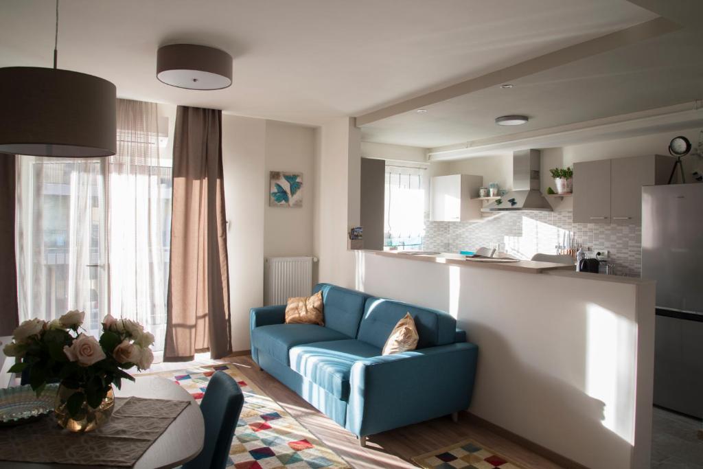 a living room with a blue couch and a kitchen at Apartment Cristian 2 in Timişoara