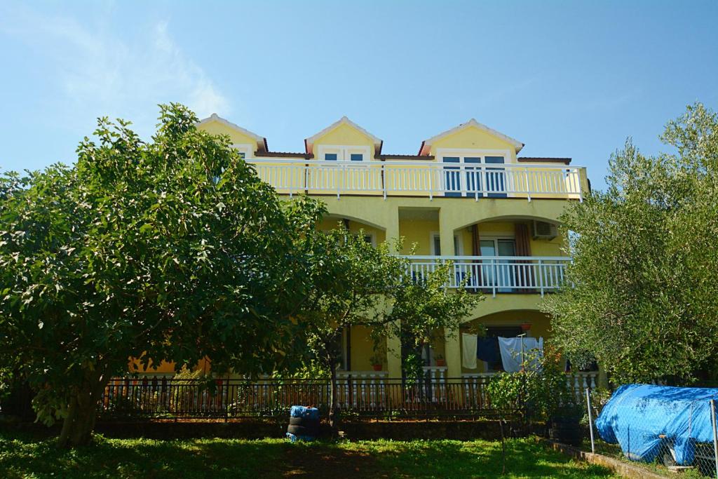 duży żółty dom z balkonem na górze w obiekcie Apartments Bosnjak w Szybeniku