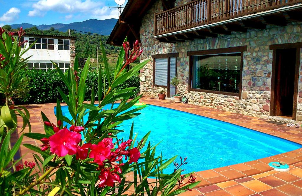 a swimming pool in front of a house with flowers at Chalet "Rec dels Noguers" in Castellciutat