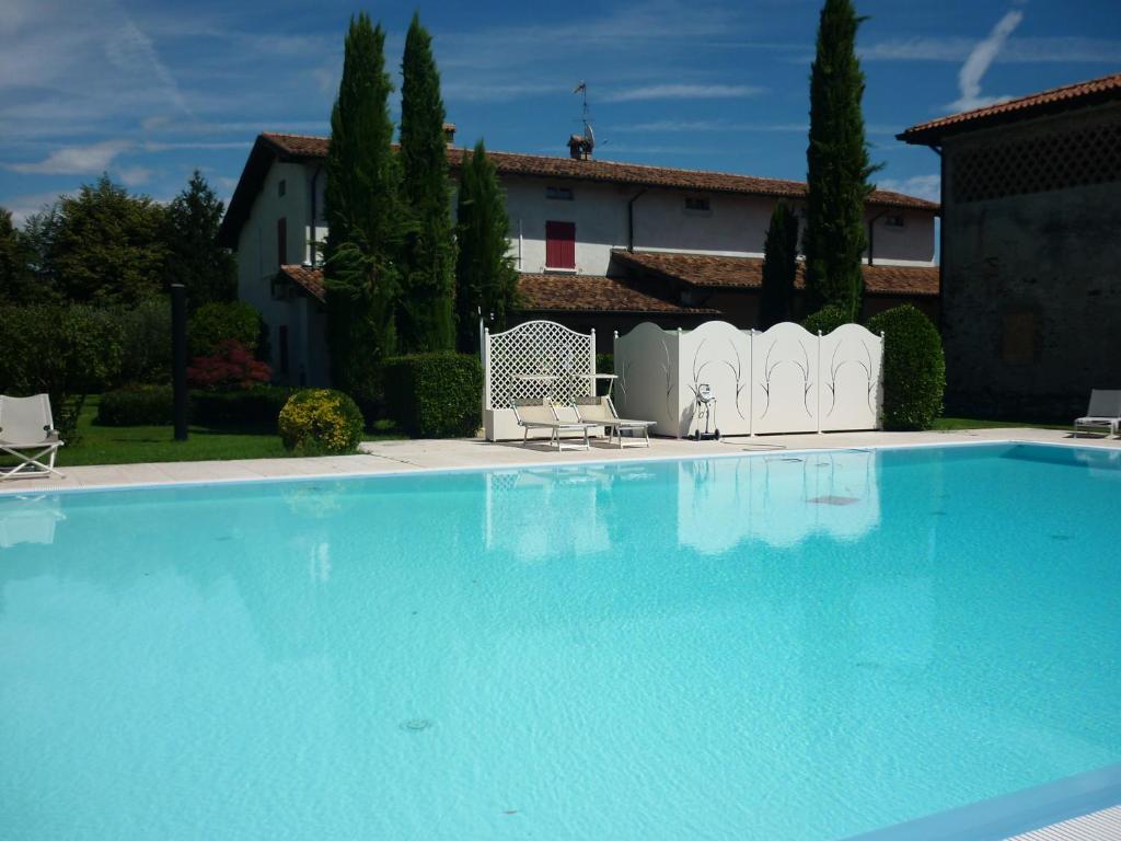 duży niebieski basen z dwoma krzesłami i dom w obiekcie Cascina Maria w mieście Desenzano del Garda