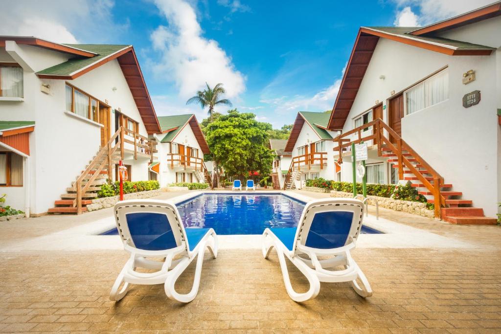 - deux chaises et une piscine en face d'une maison dans l'établissement Decameron San Luis - All Inclusive, à San Andrés