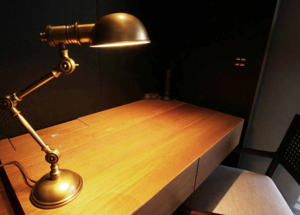 a desk with a lamp on top of a wooden table at H2O HOTEL in Kaohsiung