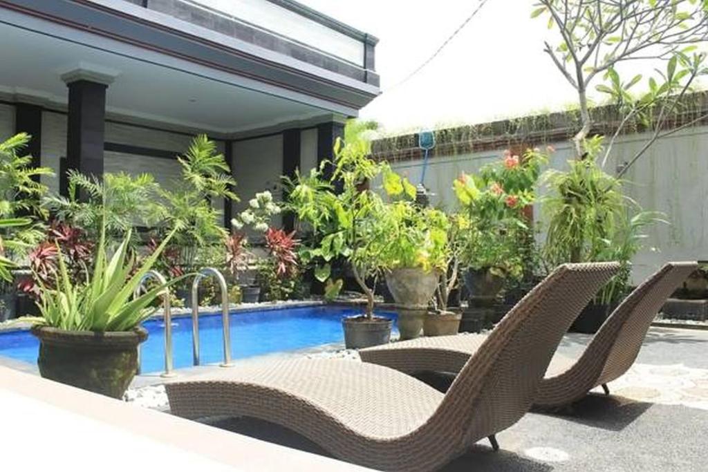 a patio with two chairs and a pool with plants at Lucky Family Villa in Ubud