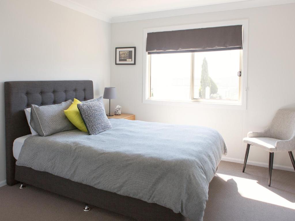 a bedroom with a bed with a window and a chair at SkyLodge Temora in Temora