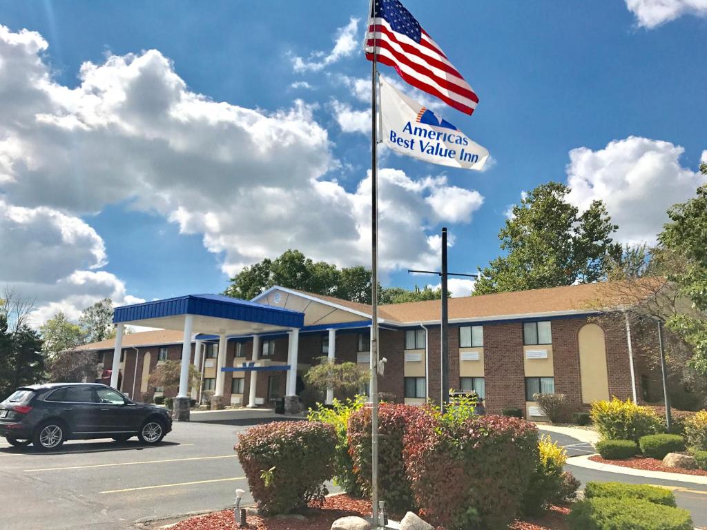 a american inn with a flag in front of it at Americas Best Value Inn & Suites - Bluffton in Bluffton