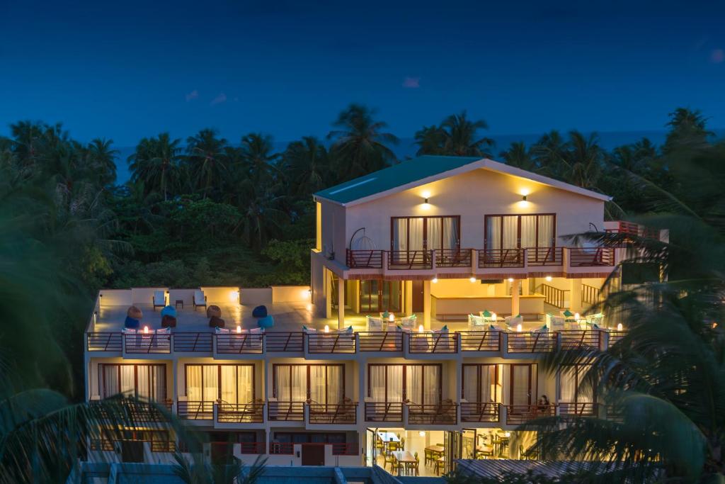 un hotel por la noche con gente sentada en el balcón en White Sand Dhigurah en Dhigurah