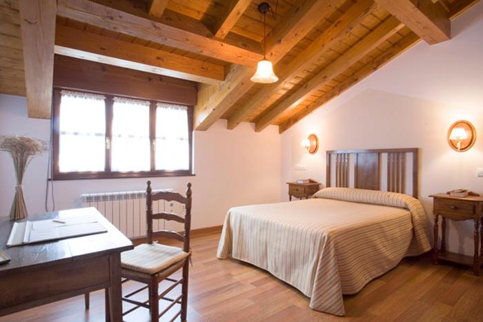 a bedroom with a bed and a table and a desk at La Fonda de Bustio in Bustio