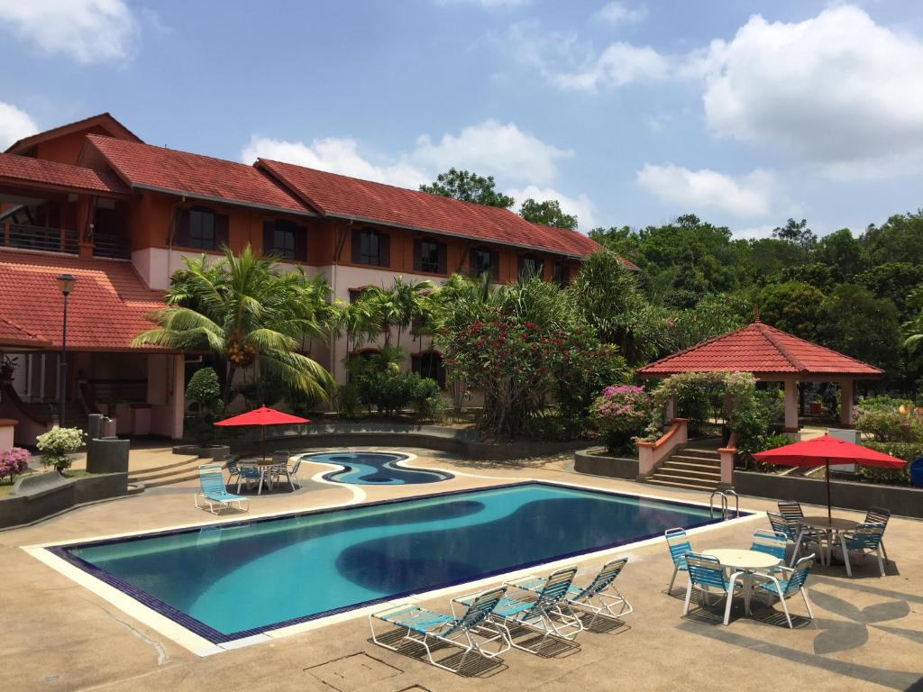 a pool in front of a building with chairs and umbrellas at Hotel Seri Malaysia Melaka in Melaka