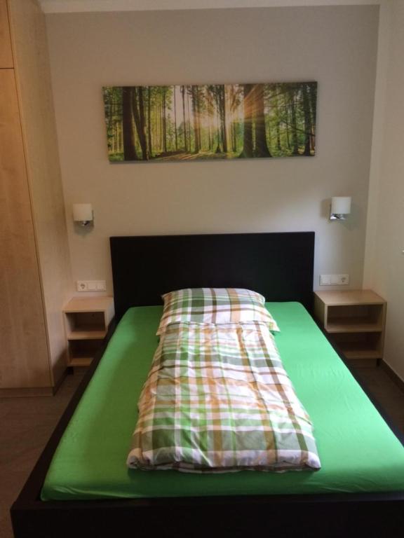a bed with a green comforter in a room at Bergcafè - Hotel Kammann in Essen