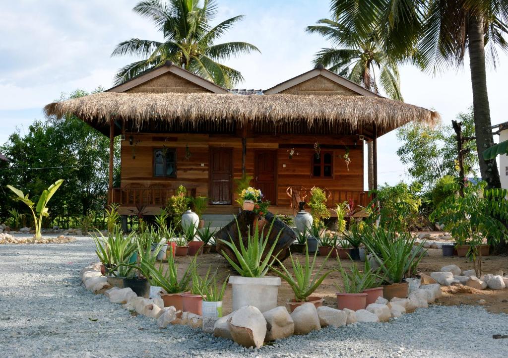 une maison avec un toit en paille et des plantes devant elle dans l'établissement Fish Island Bungalows, à Kampot