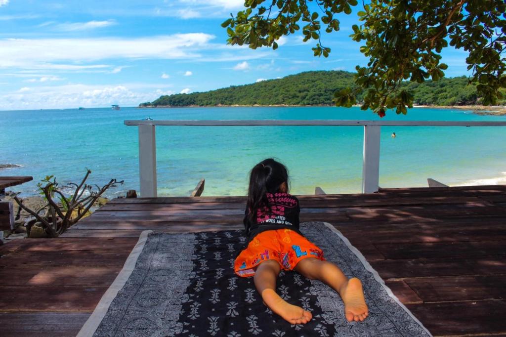 a little girl sitting on a dock looking at the ocean at Sangthain hills in Ko Samed