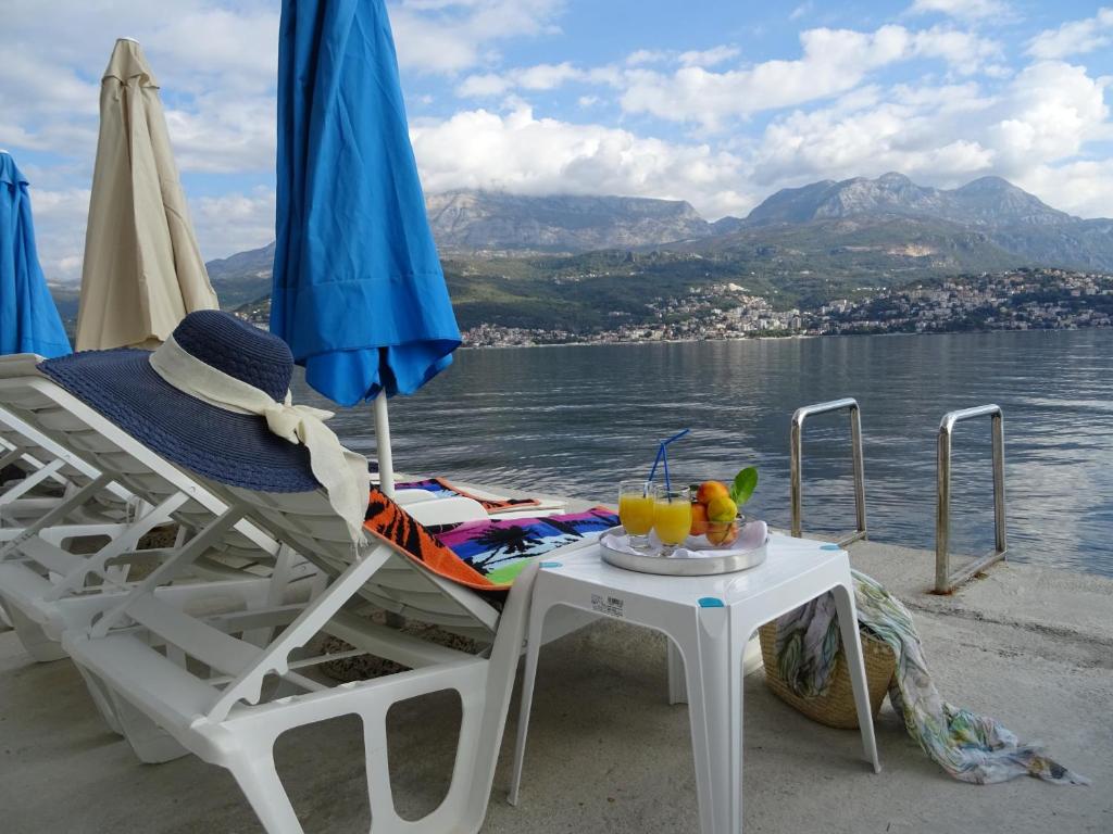 a chair and a table with drinks on a beach at Villa del Mar in Herceg-Novi