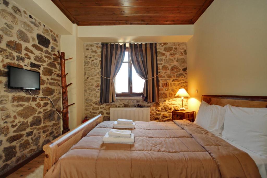 una camera da letto con un grande letto e un muro in pietra di Thea Valtessinikou a Valtessiniko