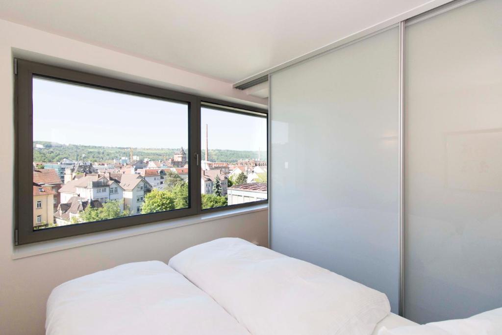 sypialnia z łóżkiem i dużym oknem w obiekcie MAVO Hospitality by Büroma Apart Apartmentvermietung GmbH Esslingen w mieście Esslingen