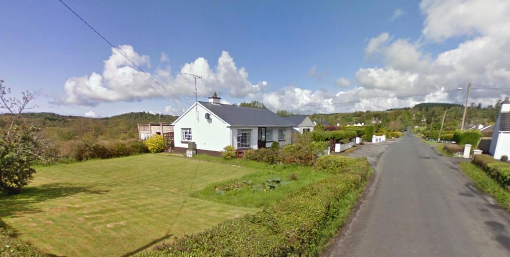 ein weißes Haus am Straßenrand in der Unterkunft Ballydevitt Retreat in Donegal