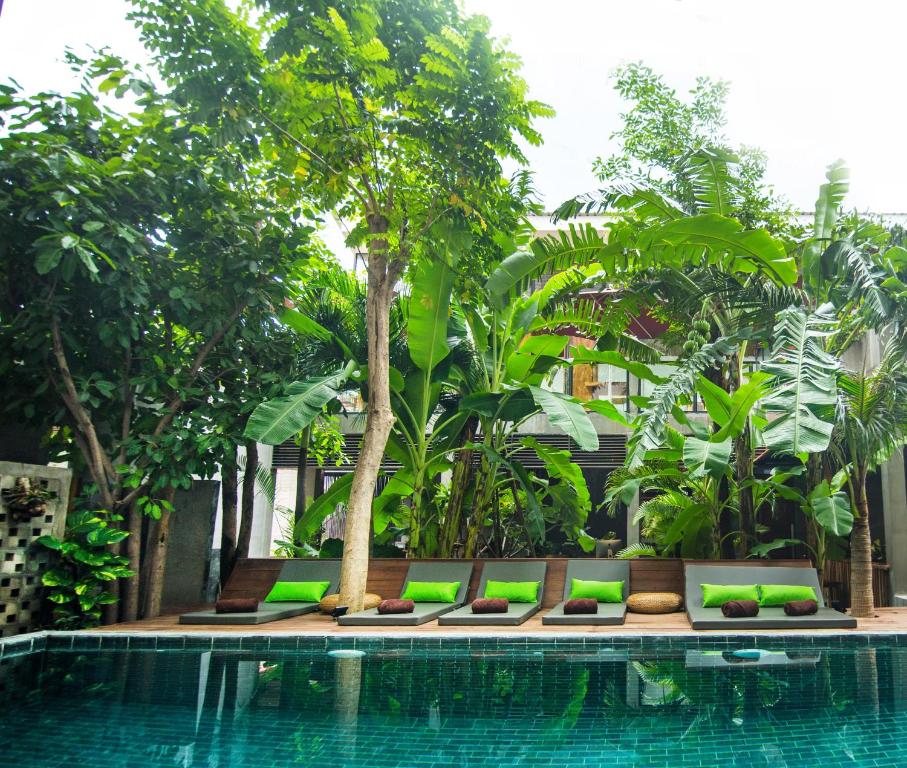 una piscina con una fila de bancos junto a un árbol en Sarina Boutique Hotel en Phnom Penh