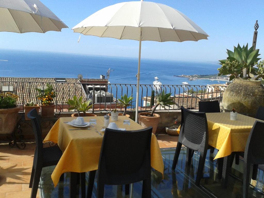 a table and chairs with an umbrella and the ocean at B&B Varò Taormina in Taormina