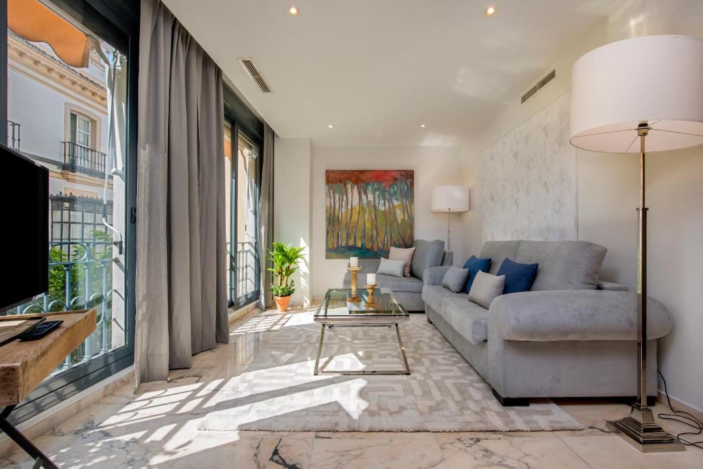 uma sala de estar com um sofá e uma grande janela em Genteel Home Vinuesa em Sevilha