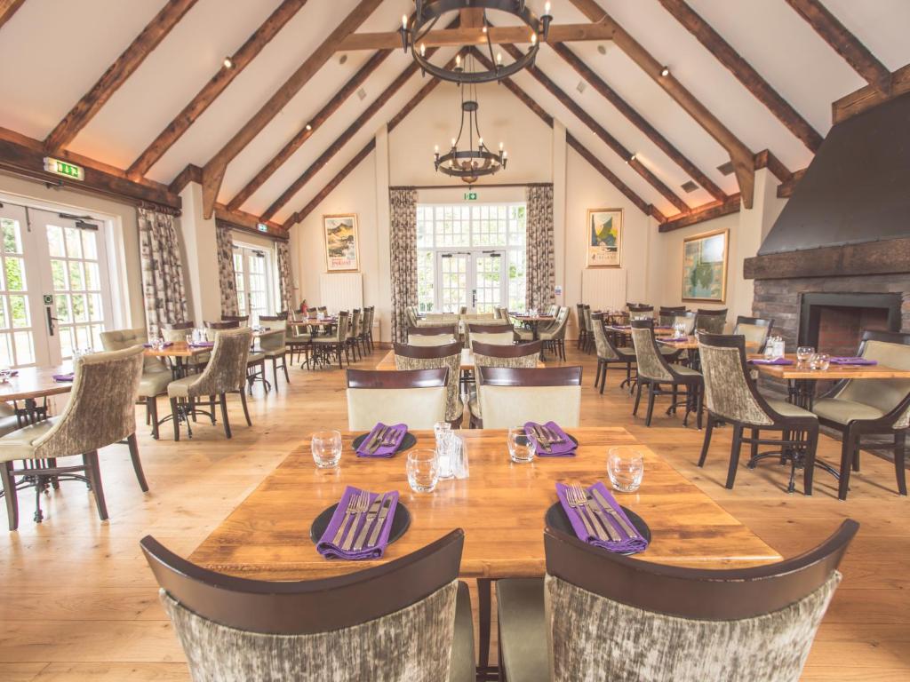 a dining room with tables and chairs and a fireplace at Ballygally Castle in Larne