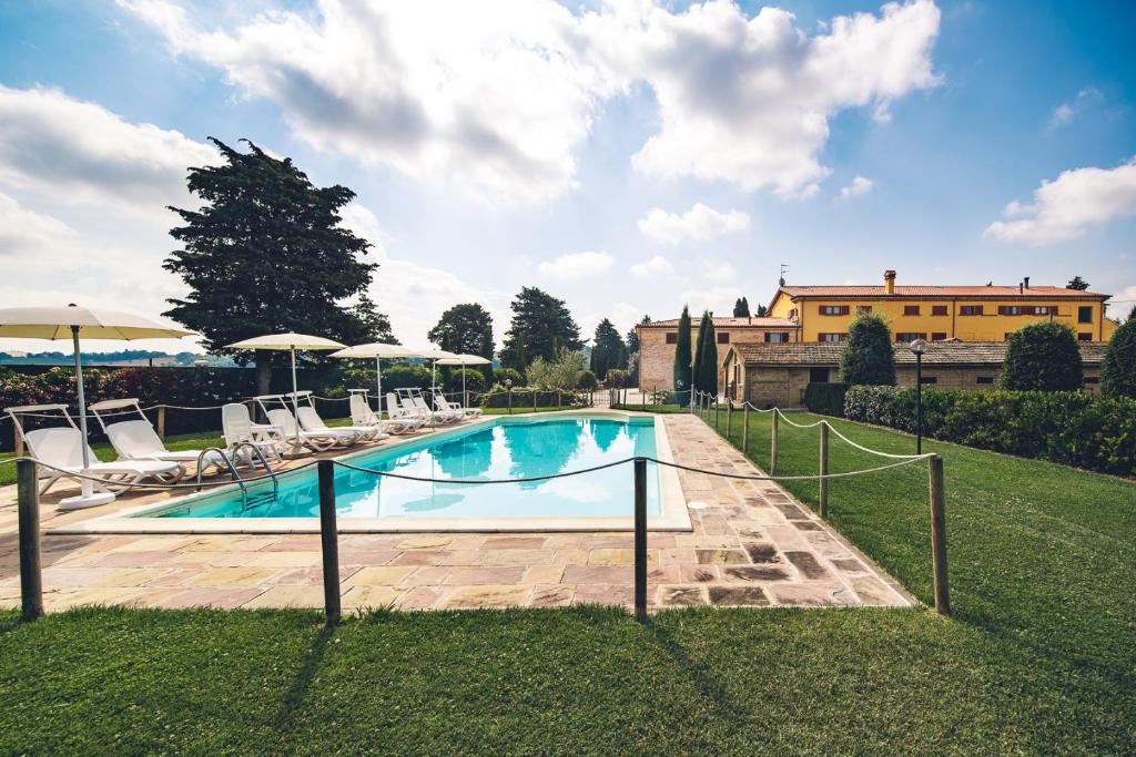 una piscina con sedie e ombrelloni in un cortile di Agriturismo Miralbello a San Lorenzo in Campo