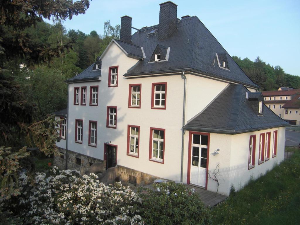 a large white house with a black roof at Postamt Lauenstein in Lauenstein