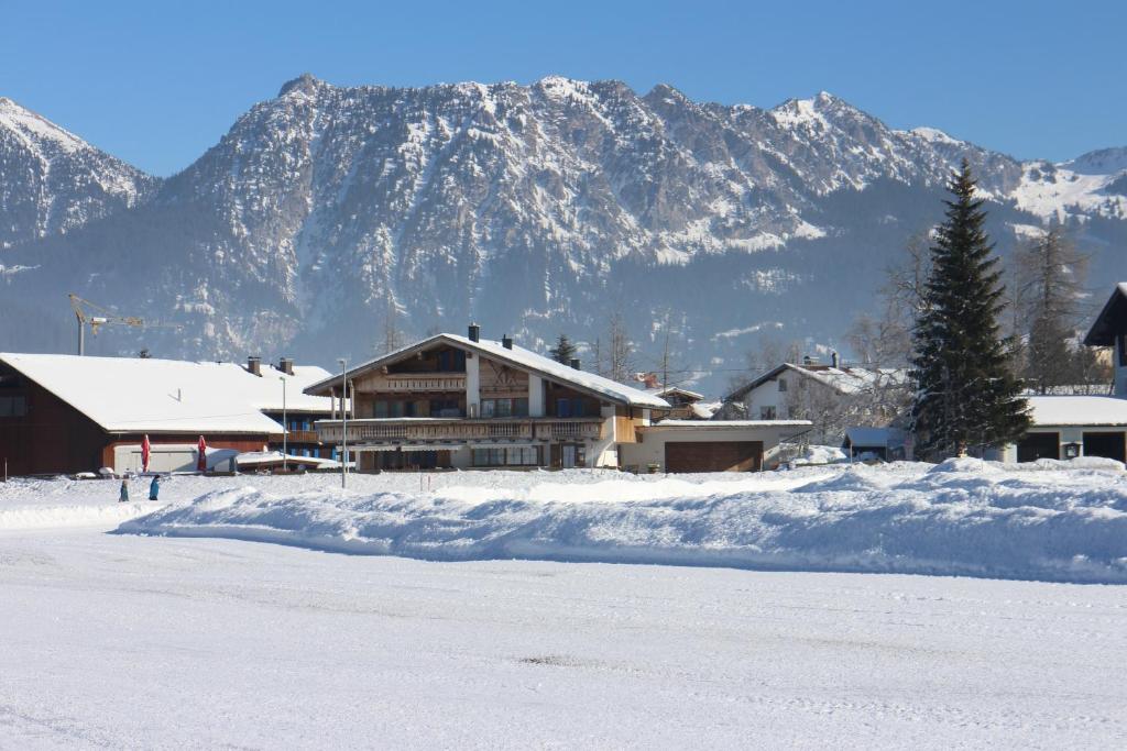 un edificio innevato con una montagna sullo sfondo di Hoamatl a Tannheim