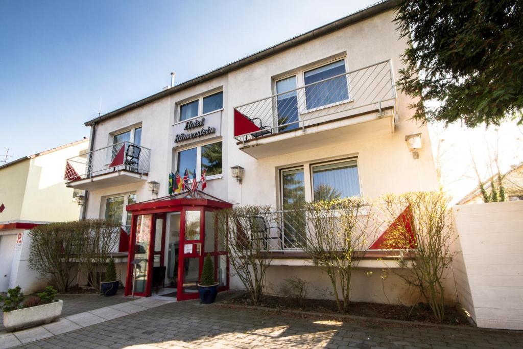 un bâtiment avec une cabine de téléphone rouge devant lui dans l'établissement Hotel Roemerstein, à Mayence