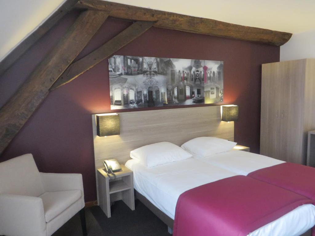een slaapkamer met een wit bed en een stoel bij Abdij Hotel Rolduc in Kerkrade