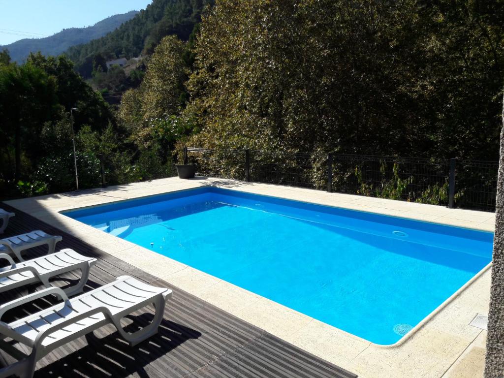 uma piscina com duas espreguiçadeiras e uma piscina em Casa Ribom no Gerês